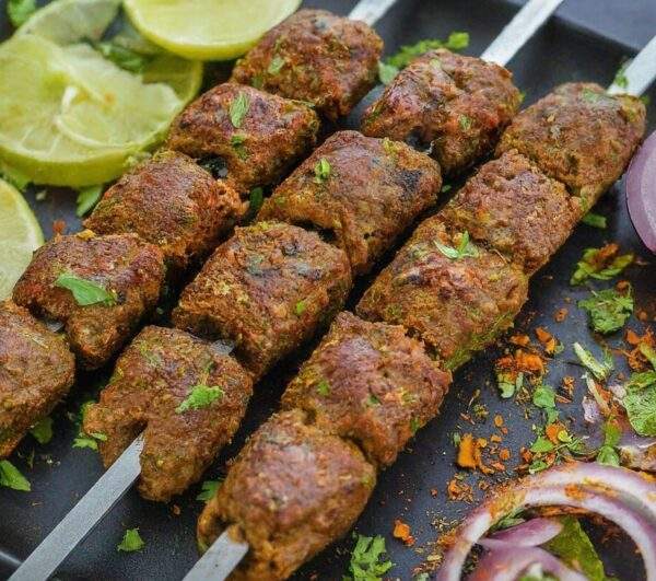 "Juicy Lamb Boti Kebab on a plate with mint chutney, showcasing halal-certified lamb marinated in Indian spices and grilled to perfection."